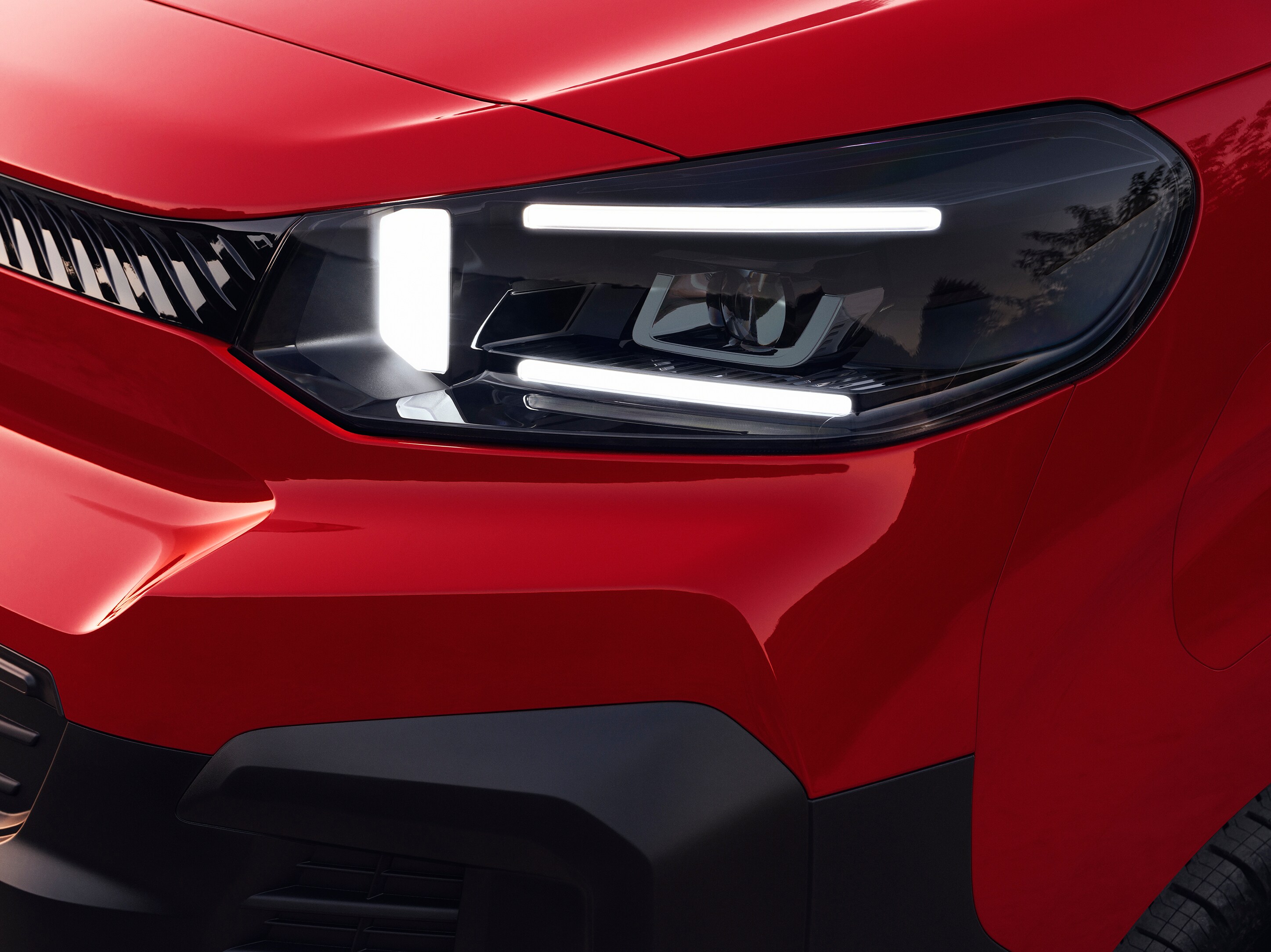 Vista exterior en detalle del faro delantero de un Citroën Jumpy rojo, mostrando diseño de iluminación moderno y estilo robusto.