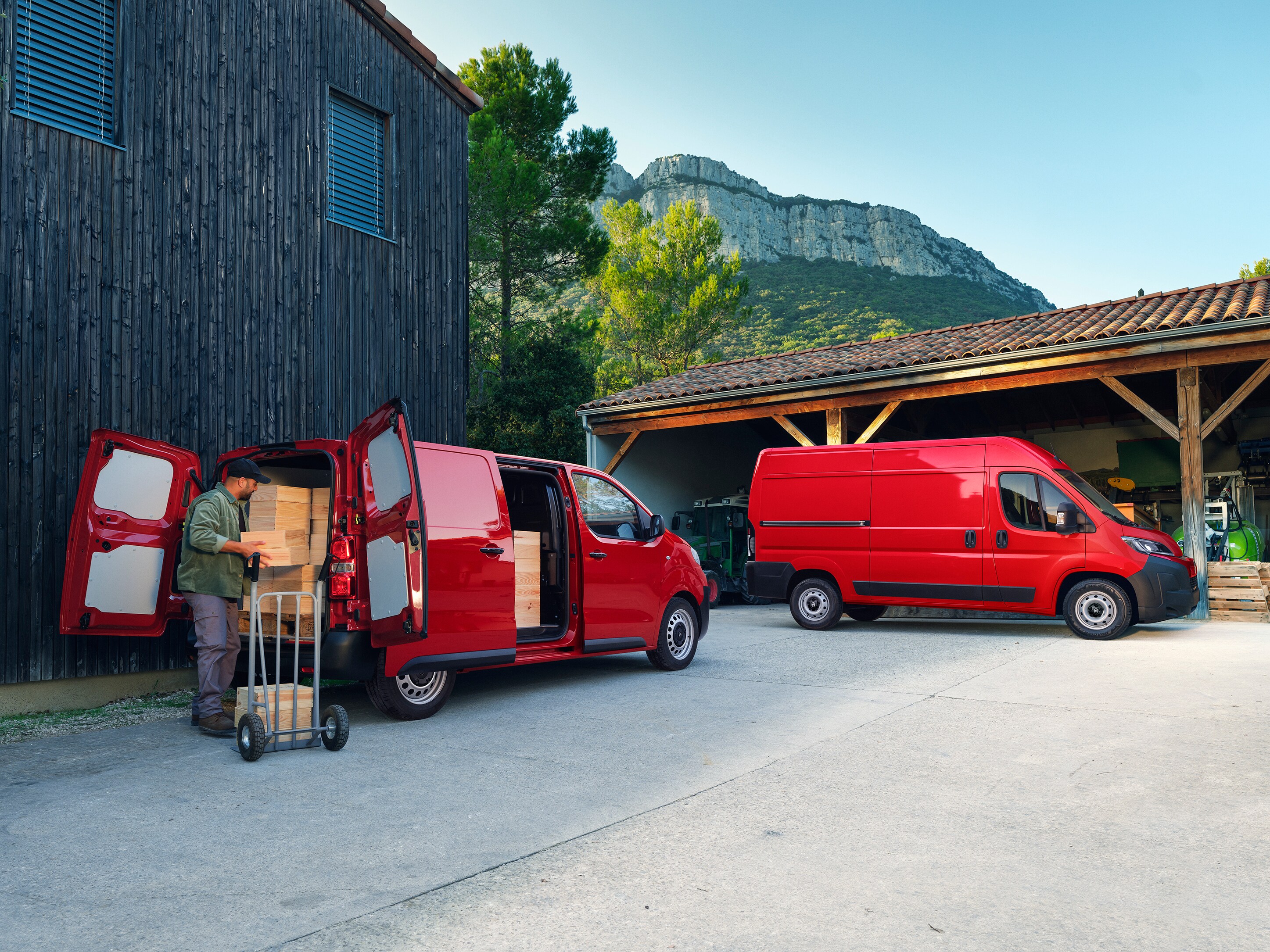 Vista exterior tres cuartos trasera de dos vehículos Citroën Jumpy rojos aparcados durante la carga, mostrando configuraciones versátiles, gran capacidad de carga e idoneidad para actividades profesionales diarias.