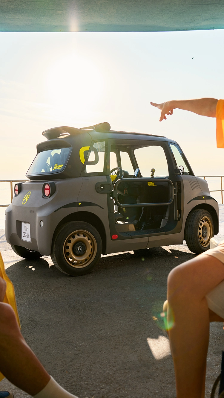 Vista lateral en playa del Citroën Ami muestra un diseño eléctrico compacto, seguro y fiable ofreciendo libertad veraniega innovadora.