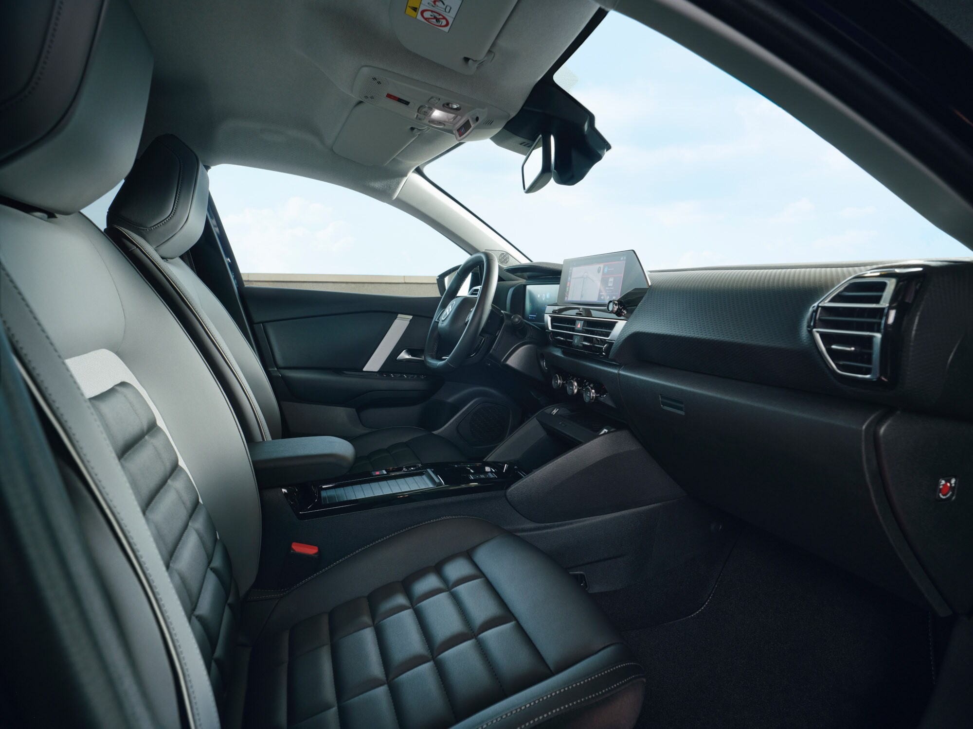 Vista interior frontal del Citroën ë‑C4 X mostrando asientos, salpicadero y pantalla central.