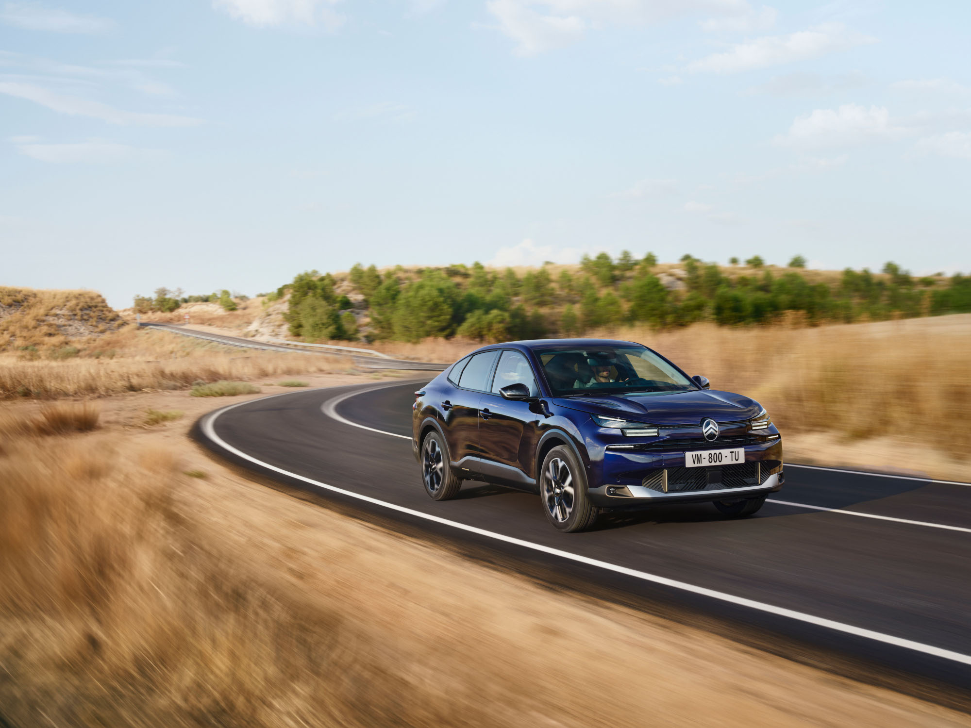 Vista frontal tres cuartos en conducción del Citroën ë-C4 X mostrando diseño fastback ágil para una movilidad con confianza y asequible.