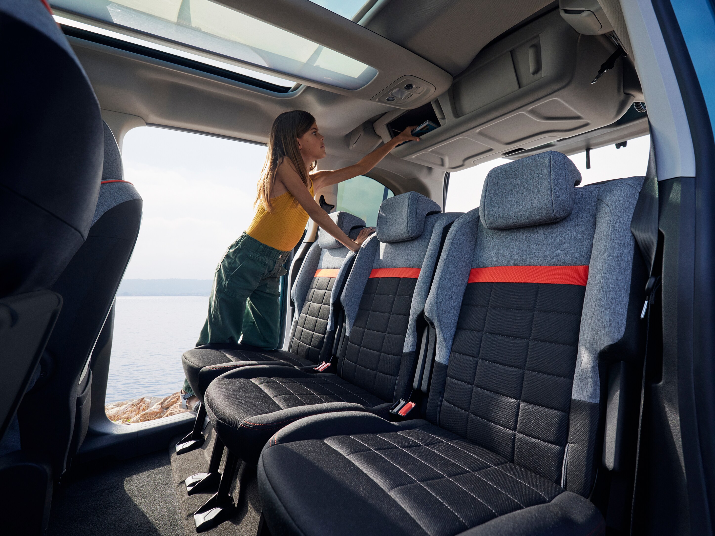 Vista interior trasera del ë-Berlingo destacando almacenamiento superior, confort, practicidad y conveniencia familiar diaria mejorada