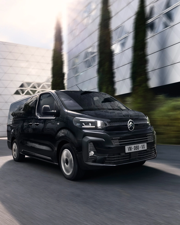 Vista frontal tres cuartos del Citroën ë‑SpaceTourer conduciendo en zona urbana, destacando su diseño dinámico eléctrico.